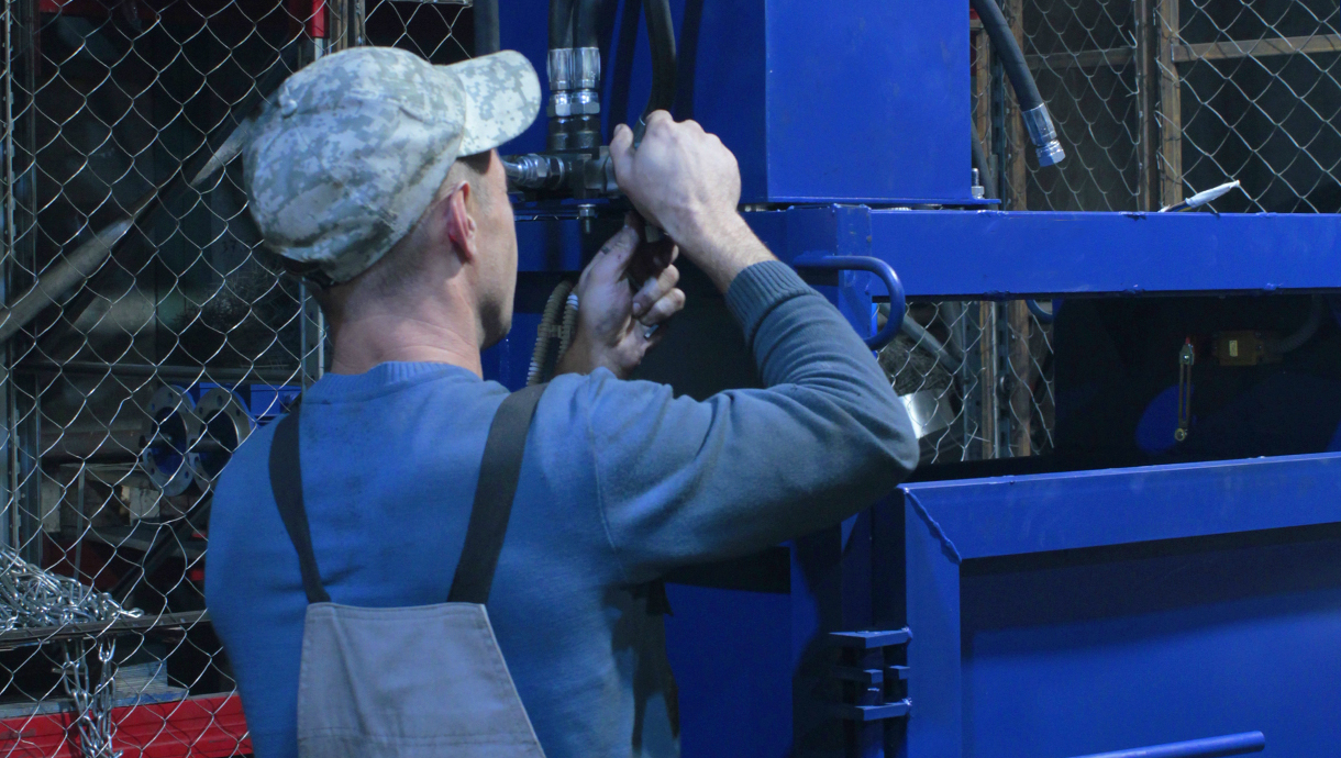Рабочий завода ремонтирует прессовое оборудование.
